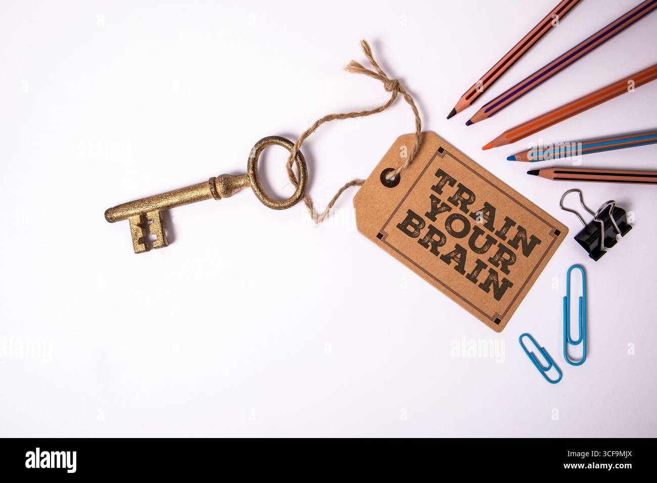 Addestra il tuo messaggio di motivazione cerebrale sull'etichetta con chiave Vintage e cancelleria su sfondo bianco. Foto Stock