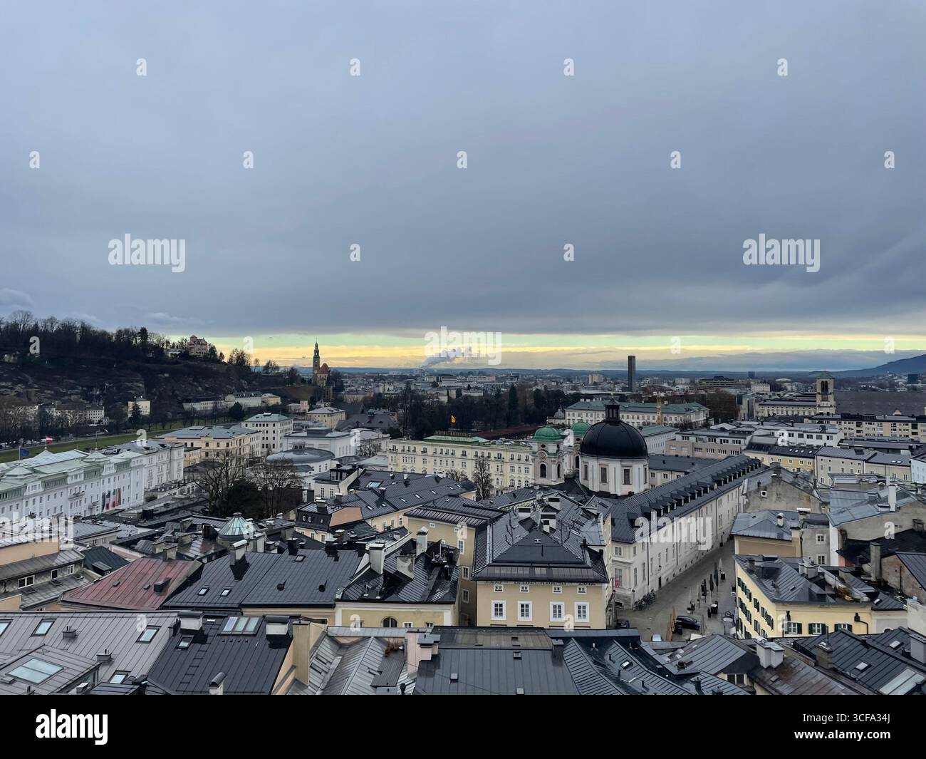 Salisburgo, Austria - 22 dicembre 2024: Una vista mozzafiato della città da un sentiero escursionistico che risale la montagna in una nuvolosa giornata invernale. - Immagine stock catturata con smartphone