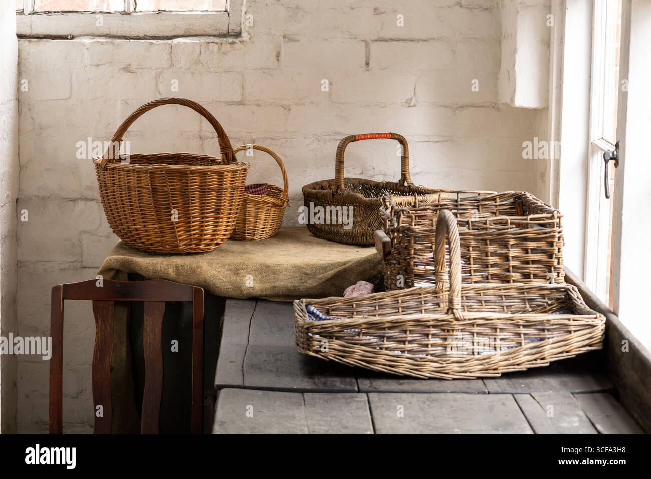 Cesti rustici in vimini su un tavolo di legno in un'accogliente sala illuminata dal sole Foto Stock