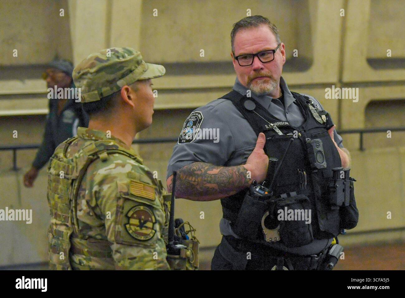 Washington, Stati Uniti. 18 agosto 2025. Un aviatore degli Stati Uniti assegnato alla Safe and Beautiful Task Force di Washington, parla con un ufficiale della polizia di transito durante una pattuglia alla stazione della metropolitana di Metro Center, 18 agosto 2025 a Washington, D.C. circa 800 membri del servizio della Guardia Nazionale sono stati schierati dal presidente Trump in una dimostrazione di forza sulla città a maggioranza democratica. Credito: Sergente Joseph Spraktes/foto dell'esercito degli Stati Uniti/Alamy Live News Foto Stock
