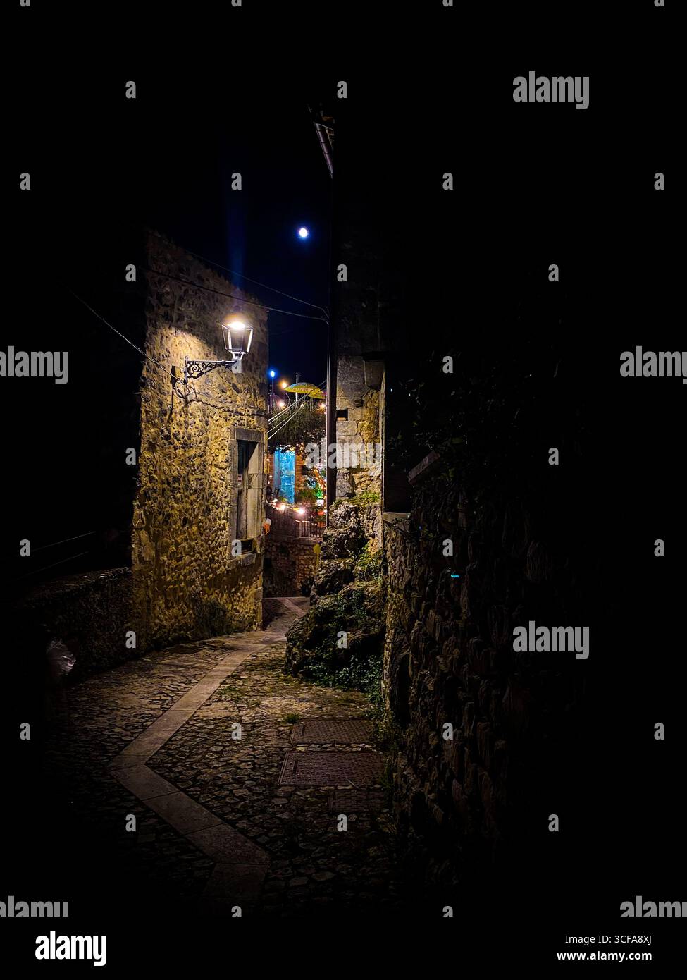Il chiaro di luna illumina lo stretto sentiero acciottolato che si snoda attraverso il borgo medievale di Pretoro, gettando ombre morbide attraverso l'antico paesaggio italiano Foto Stock
