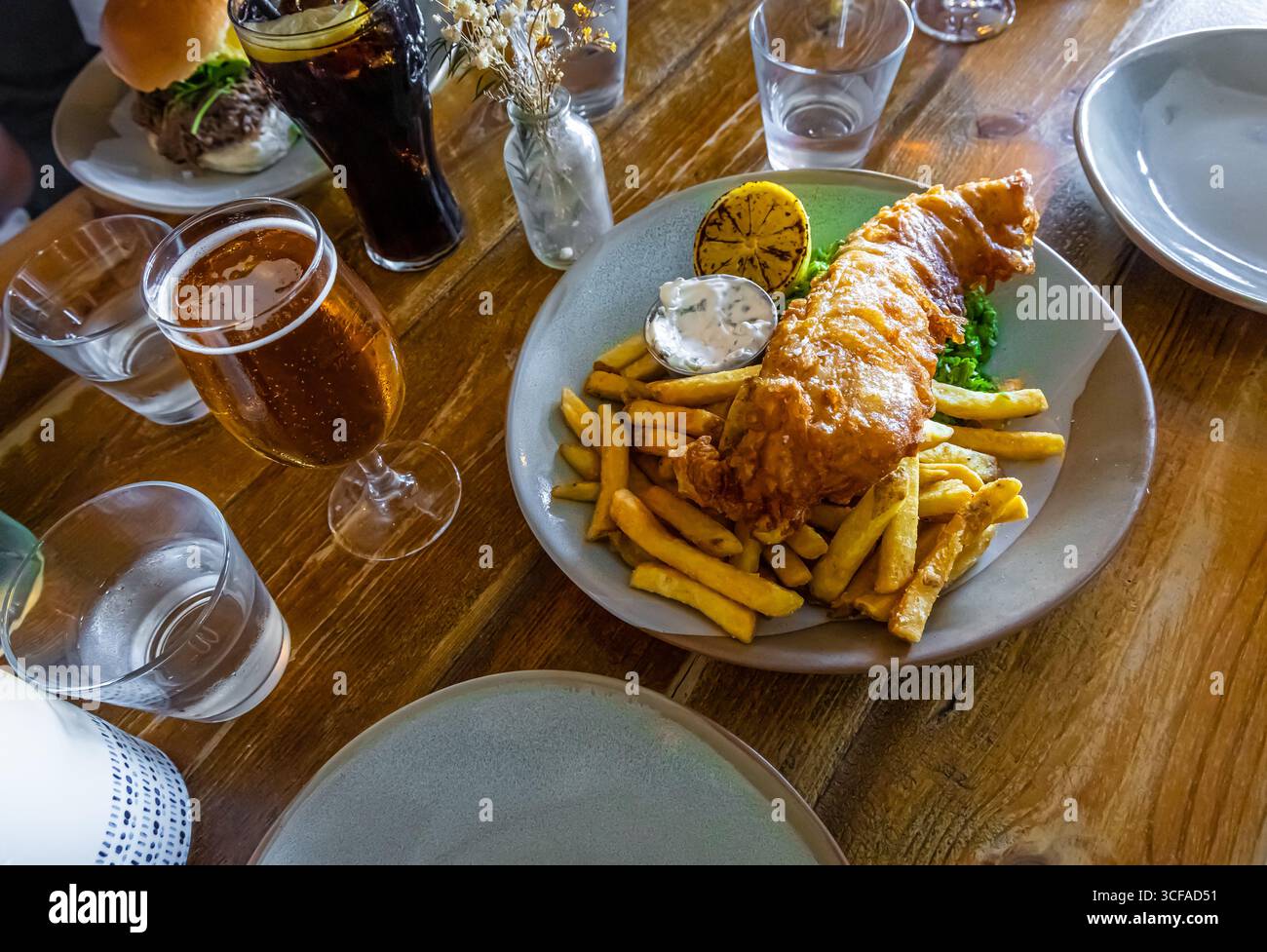 Pasto tradizionale a base di pesce e patatine con piselli moschi, salsa tartara e fetta di limone, ideale per illustrare la cucina britannica, la fotografia gastronomica o tra Foto Stock