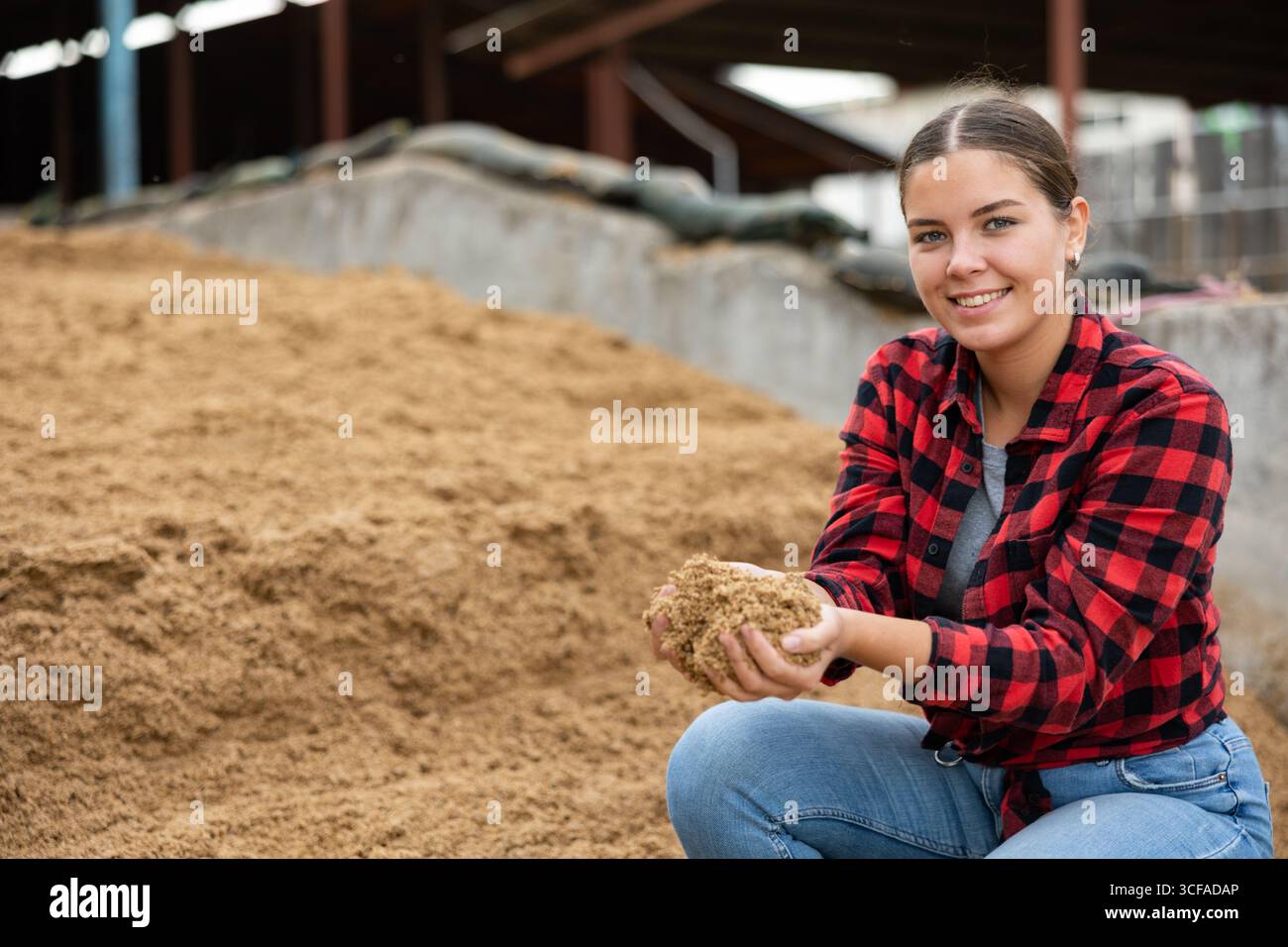 Coltivatore femmina che squatting a mucchio grande di grano esaurito del birwer Foto Stock