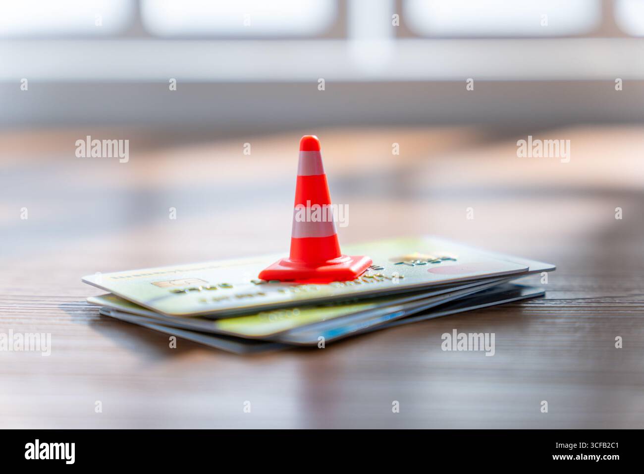 Un piccolo cono stradale su una pila di carte di credito. Concetto di prudenza finanziaria, sicurezza e debito al consumo. Foto Stock