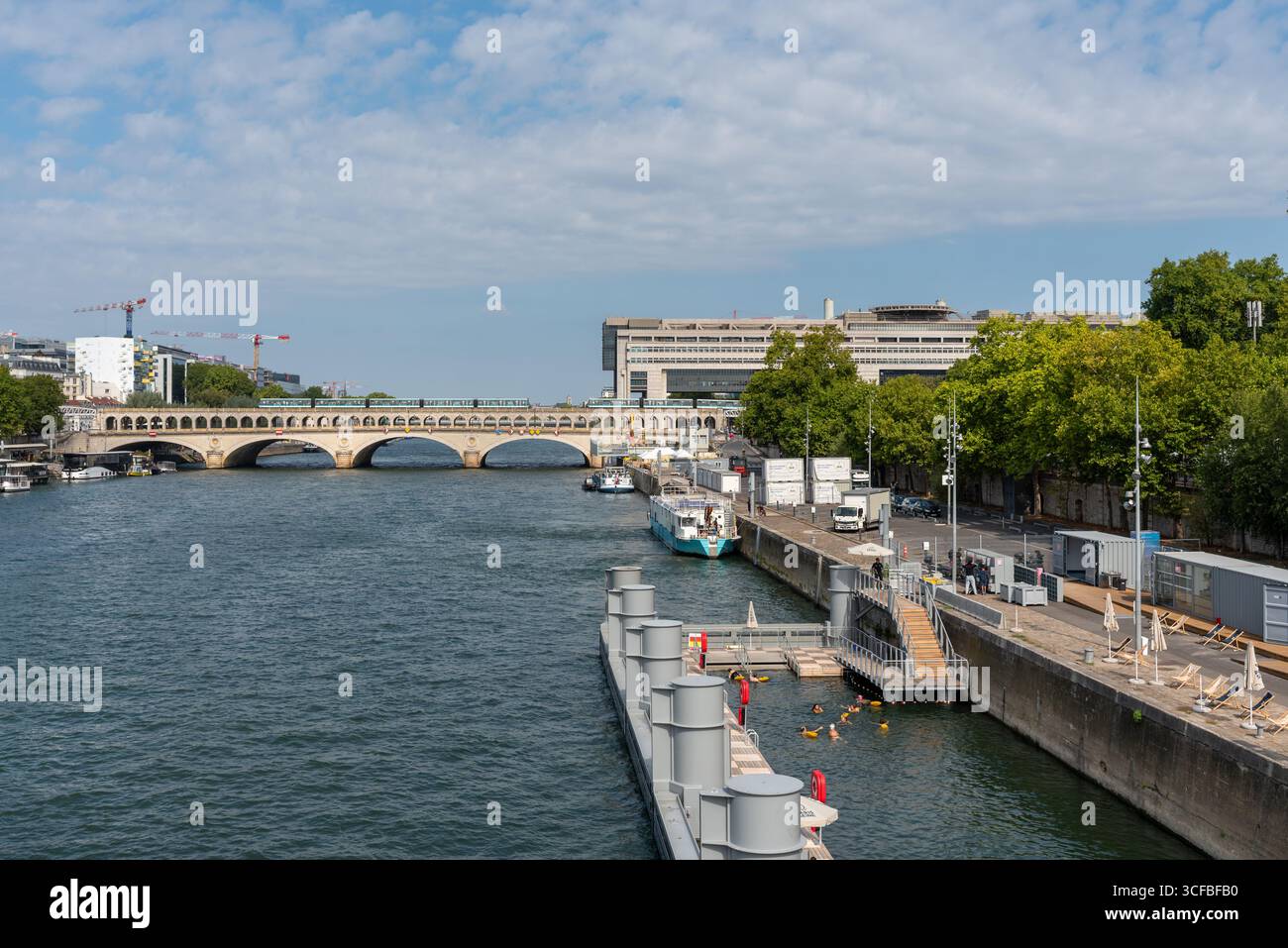 Persone che nuotano in una piscina temporanea nel fiume Senna nel 12° arrondissement di Parigi. Sullo sfondo il ministero dell'economia e delle Finanze Foto Stock