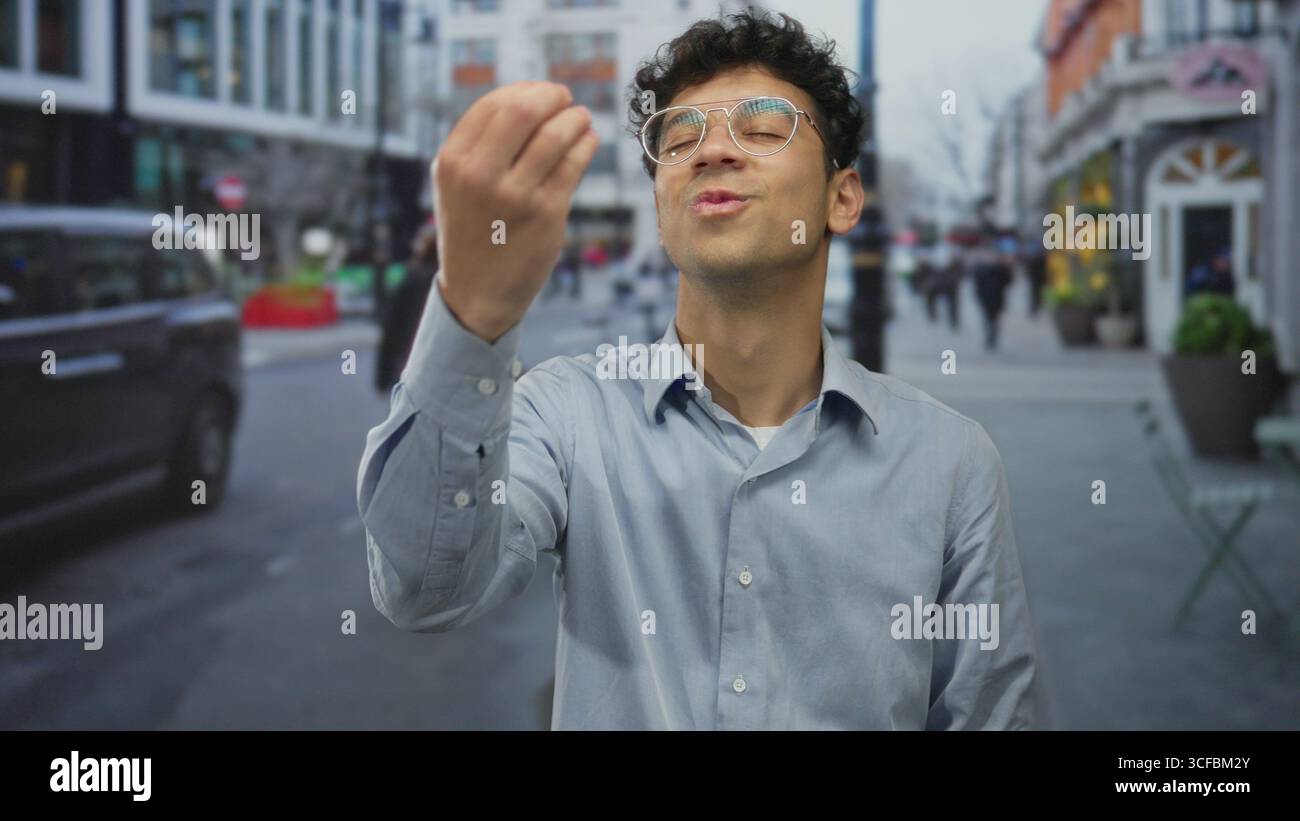 Il giovane ispanico si muove dalle dita alle labbra per fare silenzio sulle strade trafficate della città, con pedoni sfocati e taxi in cornice; tranquillo mistero. Foto Stock
