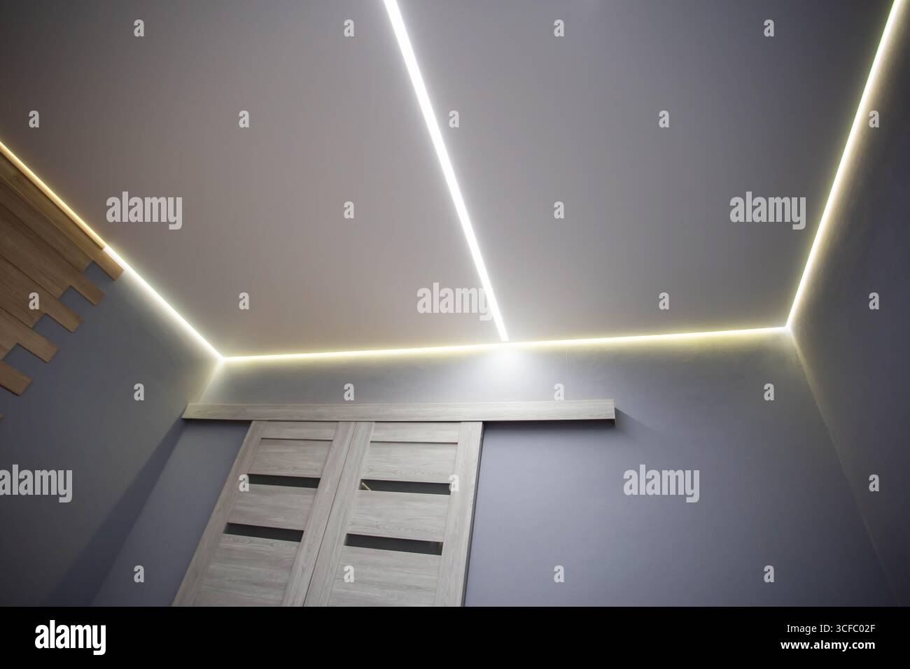 Splendido soffitto allungato moderno con linee LED gialle lungo il perimetro. Elegante soffitto di design nella hall, decorazioni Foto Stock