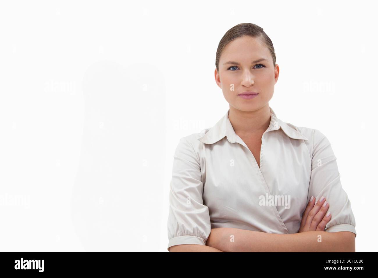 Donna in piedi con le braccia incrociate nello studio fotografico che indossa una camicetta con colletto, copia spazio Foto Stock