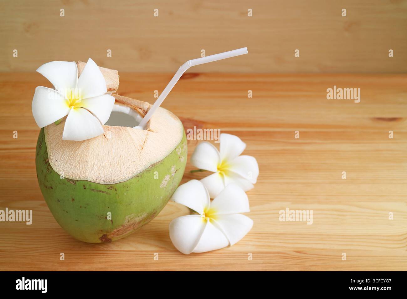 Succo di cocco fresco e naturale in guscio di cocco isolato su un tavolo di legno Foto Stock