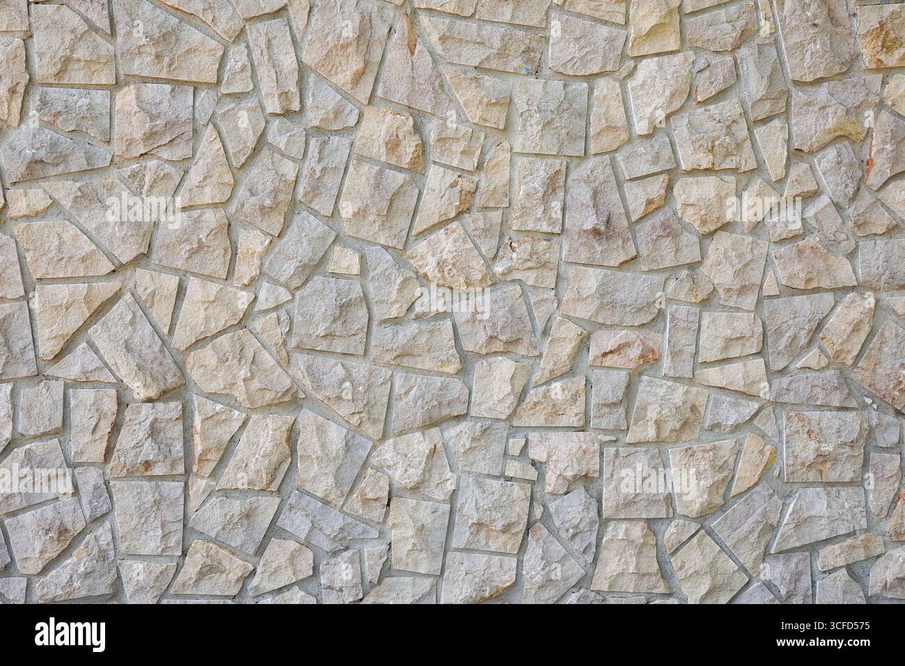 Dettaglio di una parete con un motivo decorativo di pietre grigie irregolari unite con cemento grigio. Vista frontale. Foto Stock