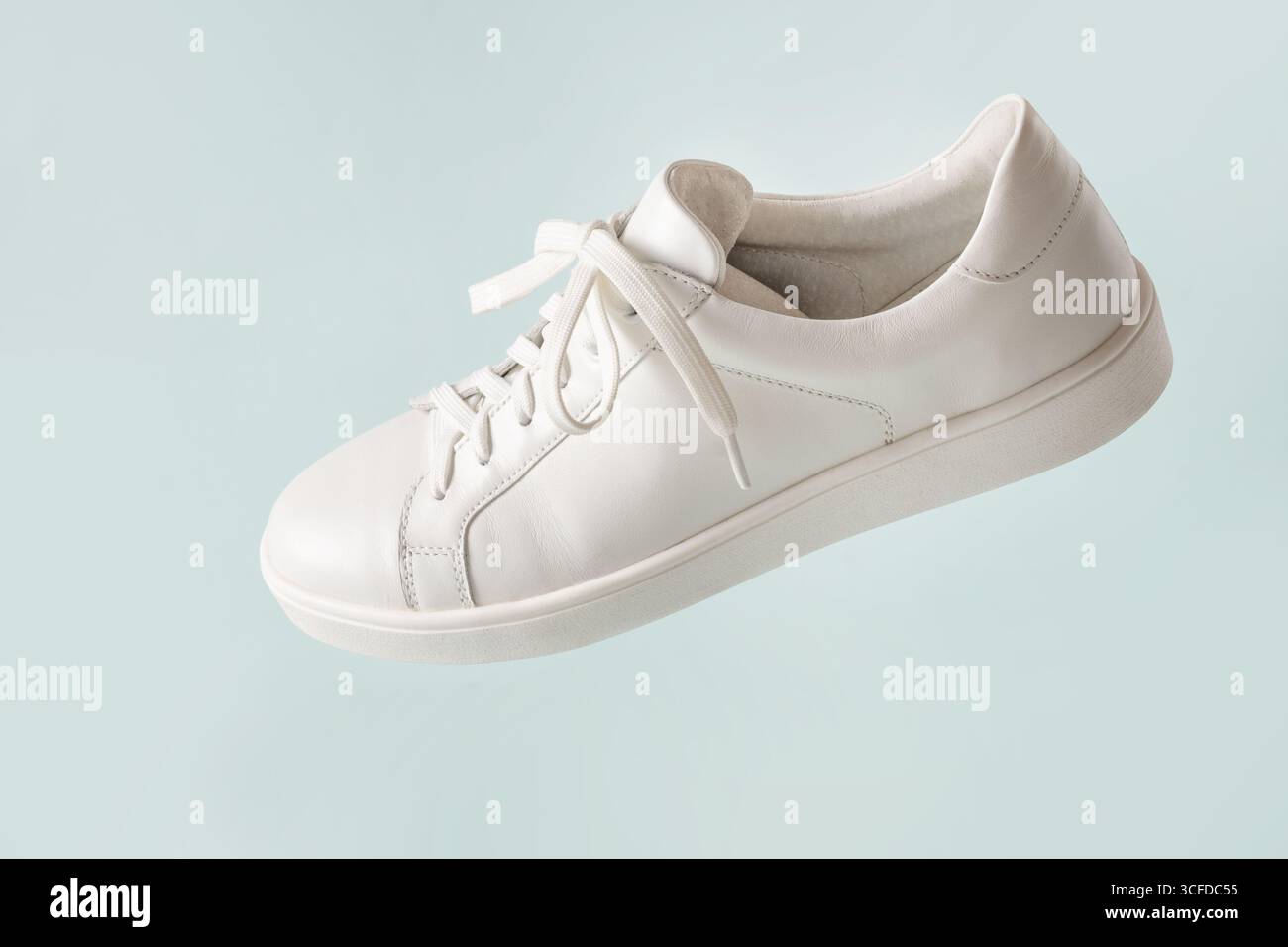Nuova sneaker bianca su sfondo azzurro. Scarpe creative stile moderno, concetto di moda. Calzature estive da donna. Copia spazio. Foto Stock