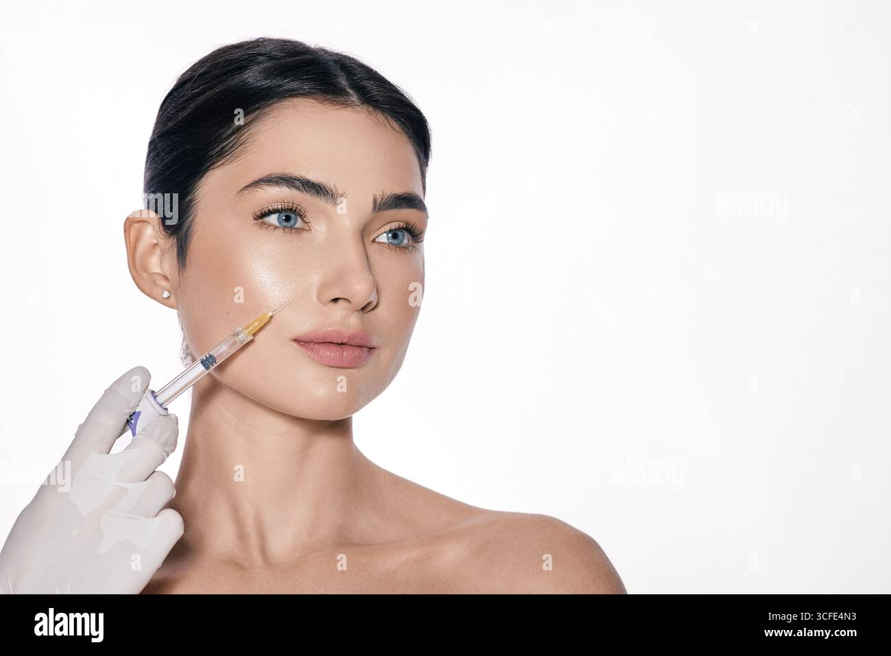 Cosmetologo che fa iniezioni di filler dermici nelle guance femminili per un viso più giovane o più bello, isolato su sfondo bianco Foto Stock