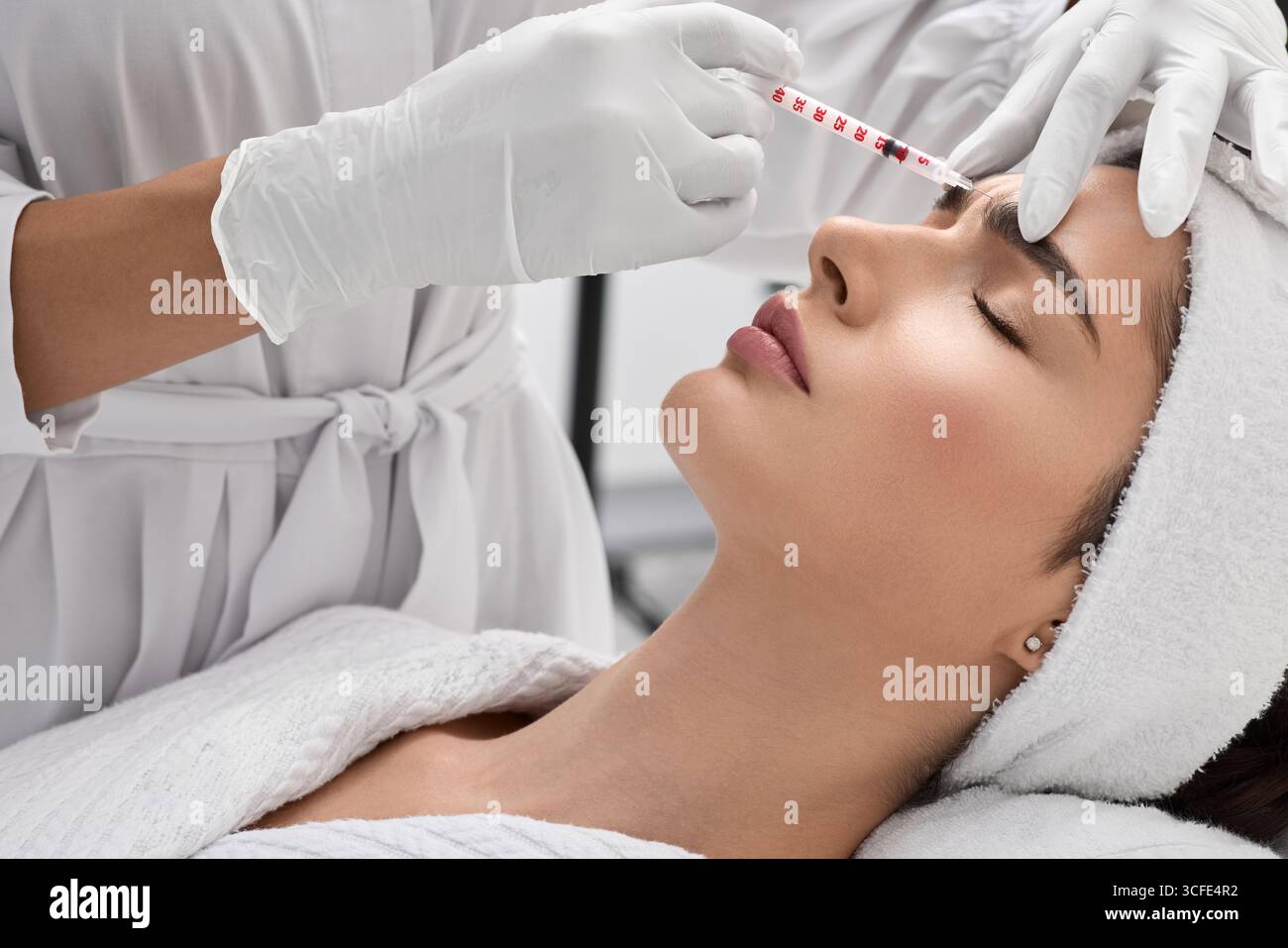 Bella donna mentre mesoterapia facciale per la rimozione delle rughe, vista laterale. Iniezioni di bellezza nella fronte della donna per bloccare le rughe mimiche Foto Stock