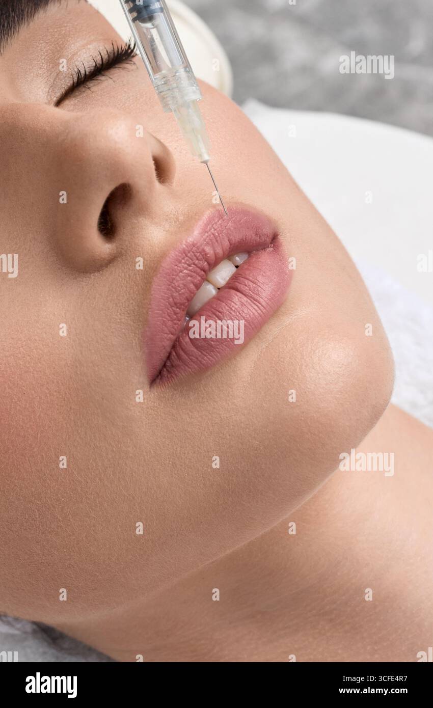 Iniezione di riempimento per una bella crescita delle labbra femminili con acido ialuronico, macro. Procedura di aumento delle labbra Foto Stock