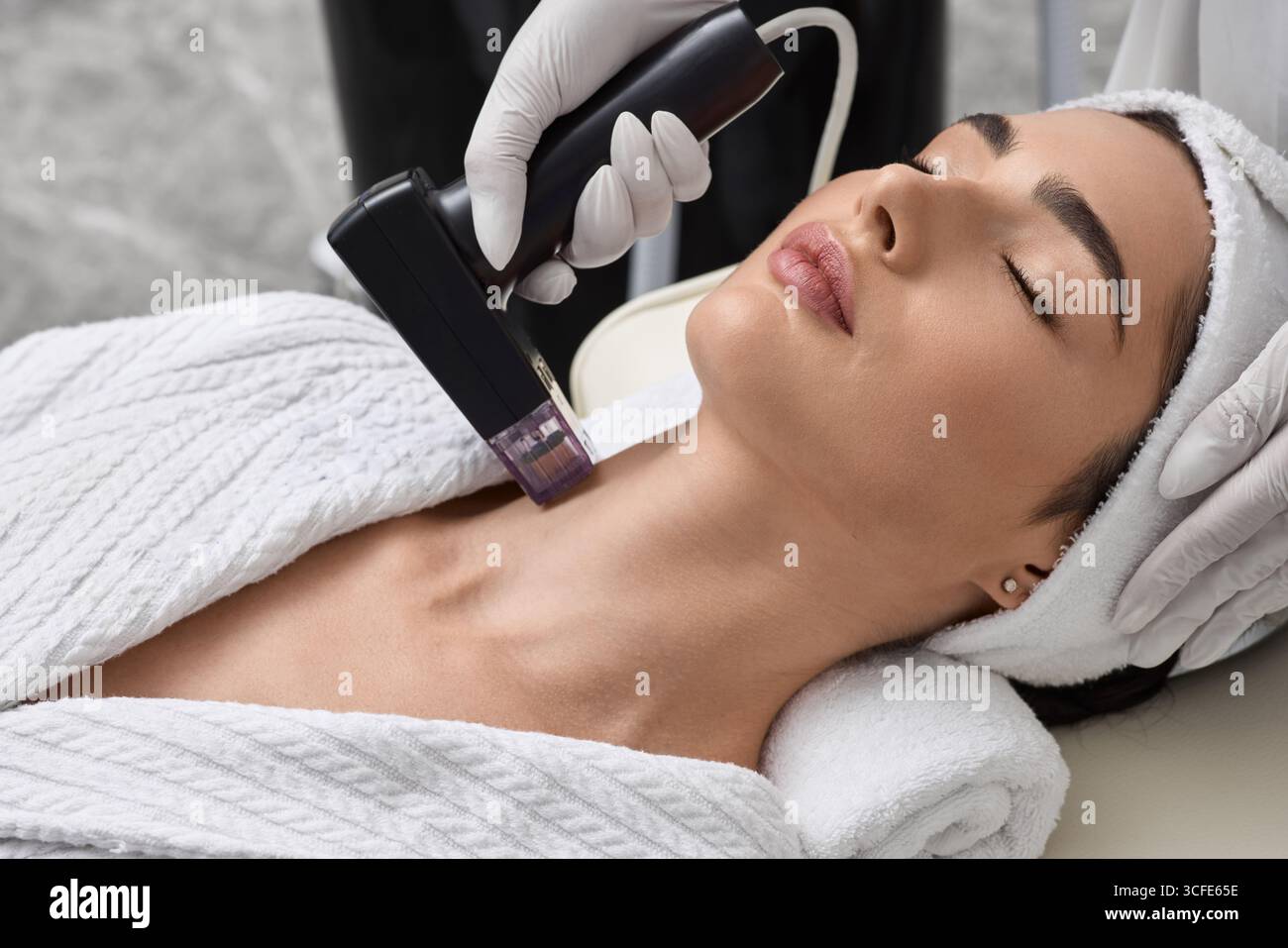 Sollievo cutaneo a radiofrequenza di una bella paziente in salone di bellezza per migliorare l'elasticità e il serraggio della pelle del collo. Sollevamento RF Foto Stock