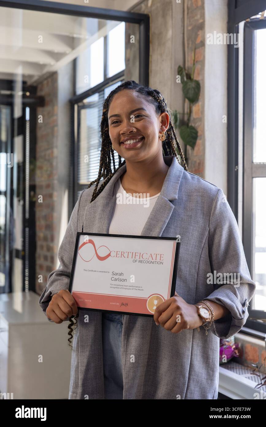 Donna afro-americana sorridente che indossa un blazer in carica mentre è in possesso di un certificato di riconoscimento Foto Stock