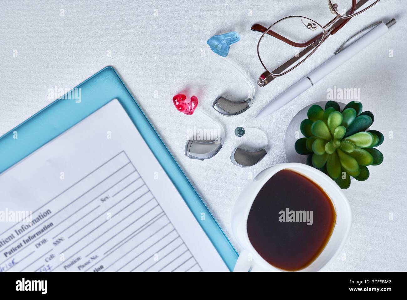 Primo piano mostra un apparecchio acustico, occhiali e una tazza di caffè presso la clinica dell'udito. Giornata lavorativa dell'audiologo Foto Stock