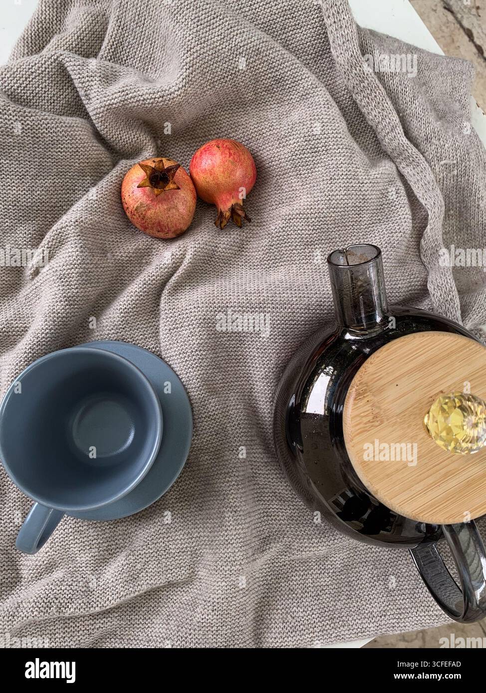 Tazza da tè vuota, teiera e due melograni su un maglione caldo. Atmosfera autunnale accogliente e relax. Vista dall'alto, disposizione piatta. Composizione autunnale. - Immagine stock catturata con smartphone