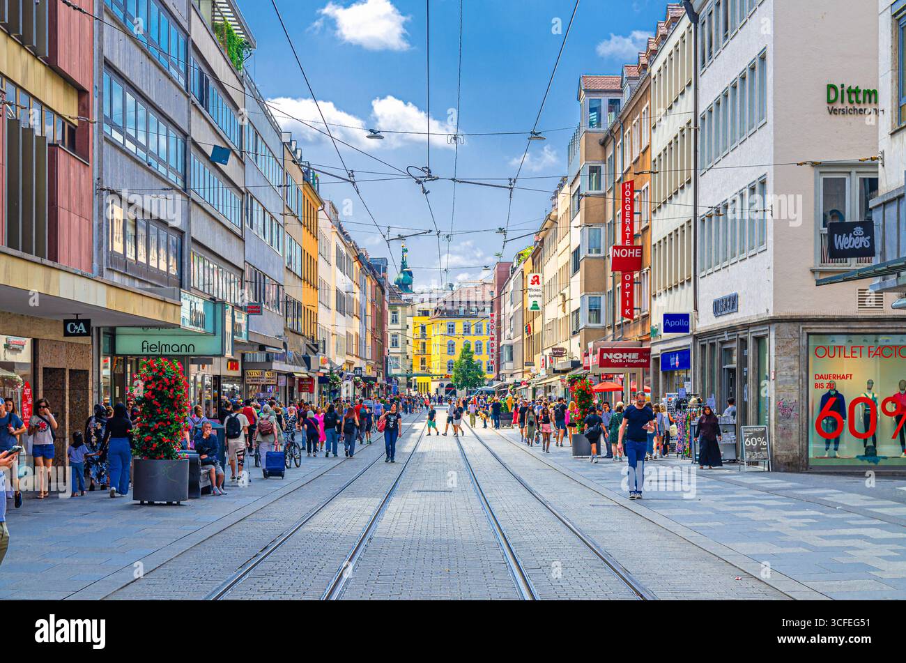 Wurzburg, Germania, 14 luglio 2024: Gente affollata che cammina lungo la strada pedonale con le rotaie del tram, turisti che passeggiano lungo la strada dello shopping con negozi e negozi Foto Stock