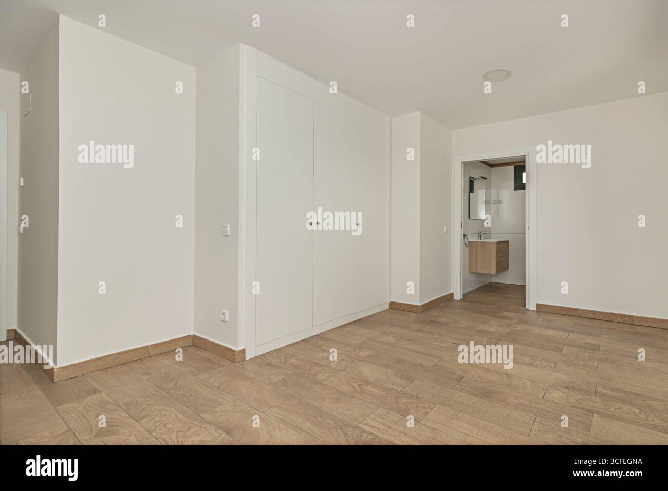 Camera da letto principale non arredata con moderni armadi scorrevoli laccati bianchi e maniglie cromate minimaliste Foto Stock