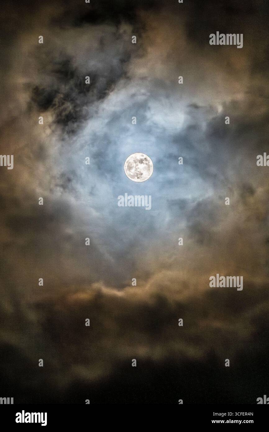 La luna piena, vista attraverso una breve pausa tra le nuvole in una notte selvaggia e tempestosa (Regno Unito) Foto Stock