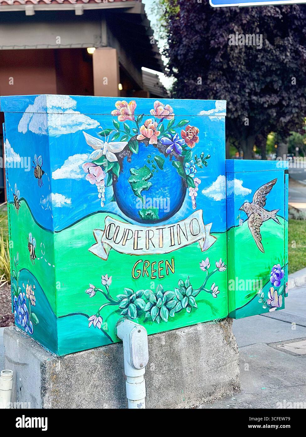 Una cassetta di servizio dipinta con colori vivaci che presenta una farfalla monarchica, fiori, colline verdi e cieli blu, catturati in un angolo di strada. - Immagine stock catturata con smartphone