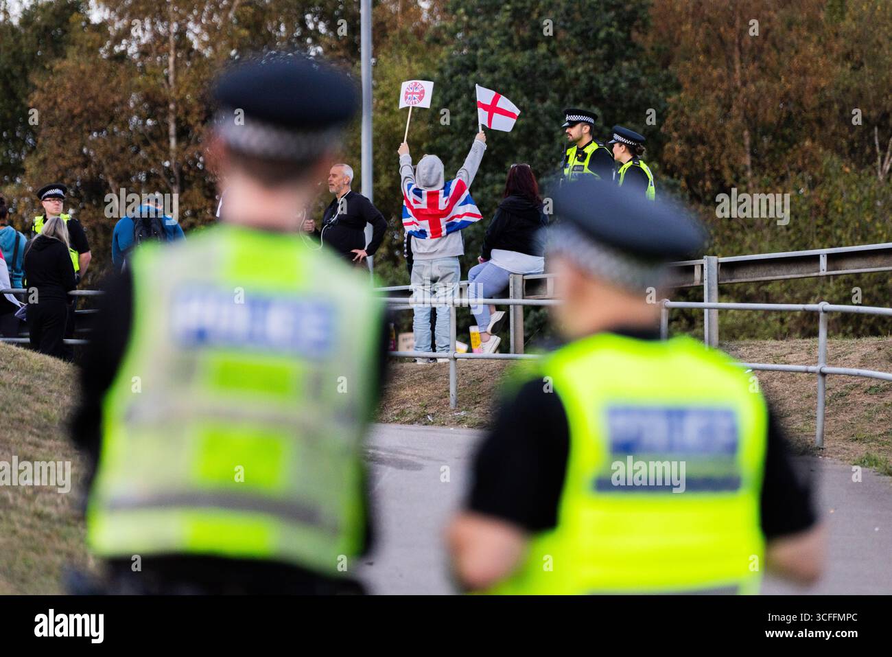 Leeds, Regno Unito. 22 AGOSTO 2025. La polizia osserva i manifestanti anti anti-migranti riuniti con le bandiere fuori dal Britannia Hotel a Seacroft, Leeds, per il quinto venerdì consecutivo. Un uomo è stato arrestato per aggressione comune dopo aver interferito con i manifestanti contro-migranti riuniti. Credito Milo Chandler/Alamy Live News Foto Stock