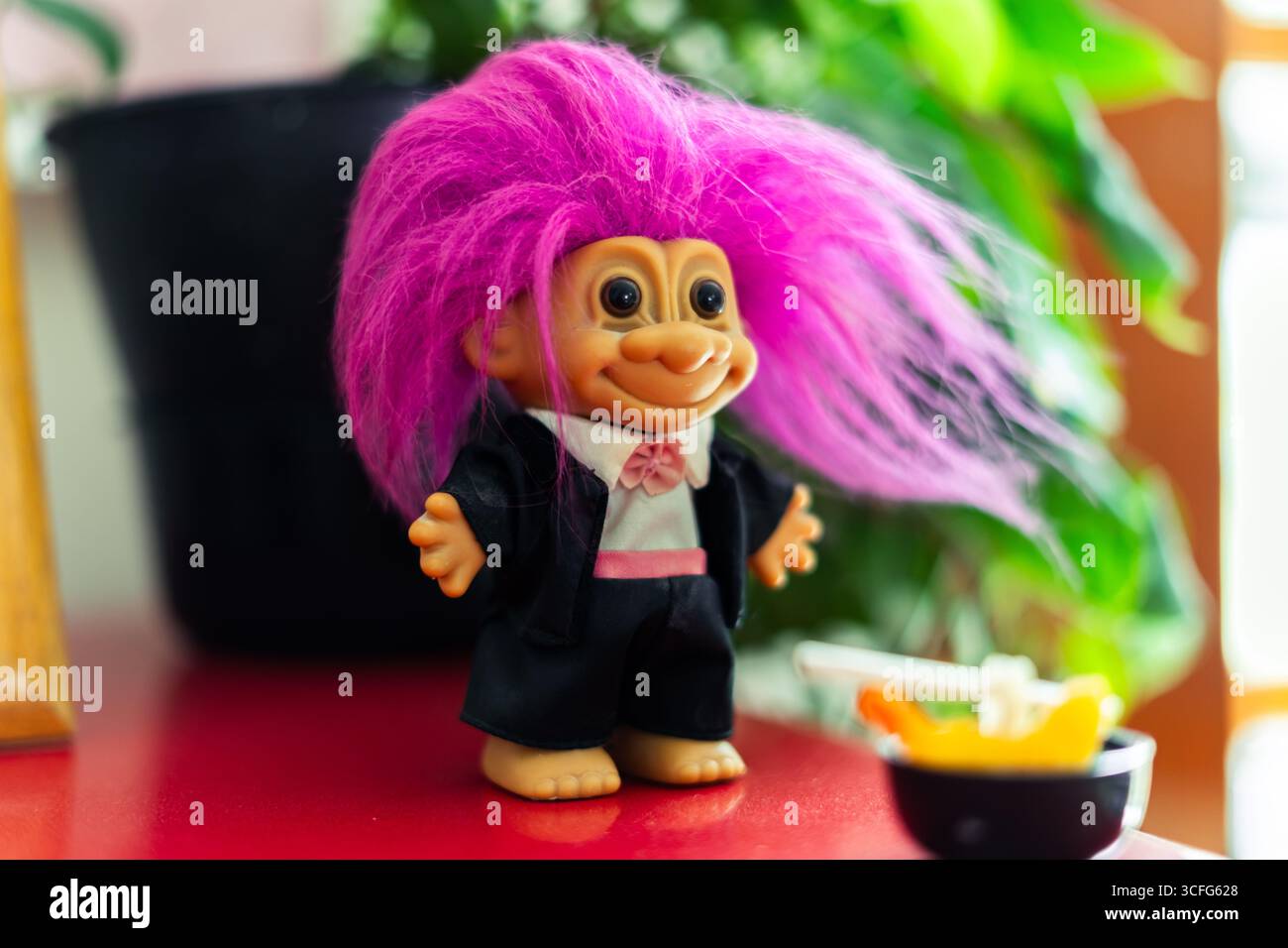 Bambola troll colorata con capelli rosa su un tavolo. Foto Stock