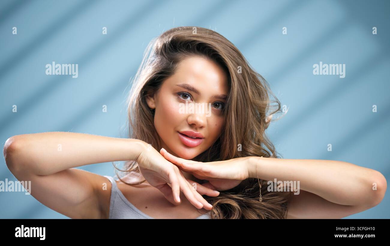 La giovane donna dalla pelle radiosa sta dimostrando una routine di cura della pelle, circondata da una luce soffusa e da un'atmosfera rilassante, che mette in risalto il suo beau naturale Foto Stock