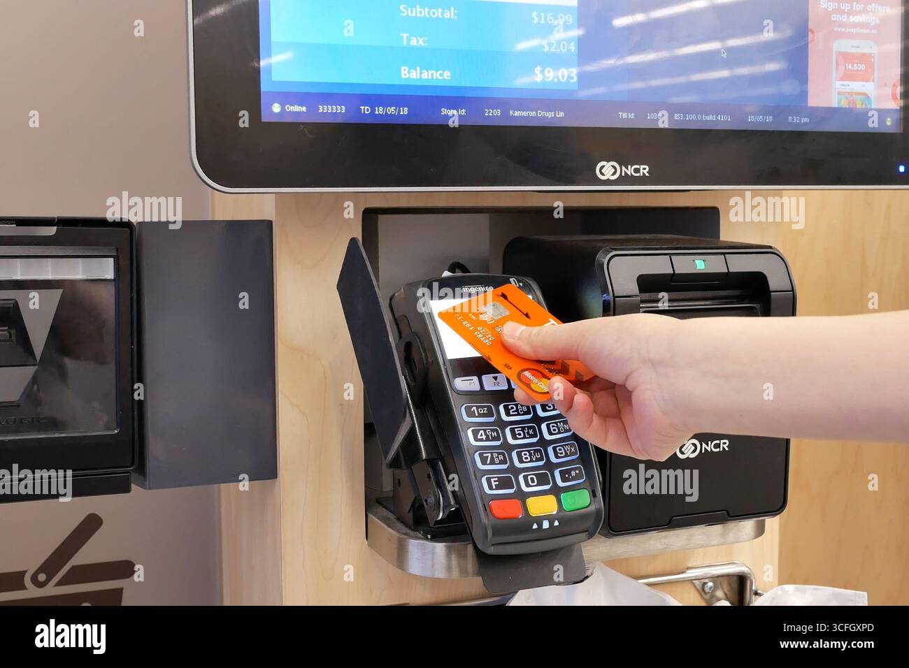 Primo piano di una donna che paga il cibo toccando la carta di credito al banco del check-out. Foto Stock