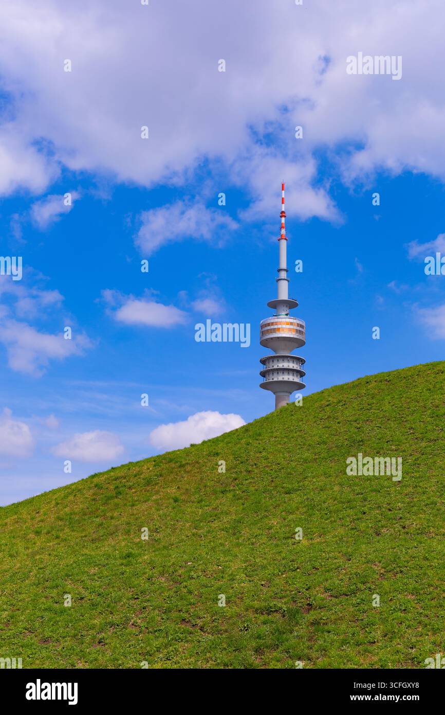 Monaco di Baviera, Germania - 2 aprile 2025: Olympiaturm (torre Olympia) al parco Olympia. Guardando in alto attraverso gli alberi del parco. Costruito per la partita olimpica Foto Stock