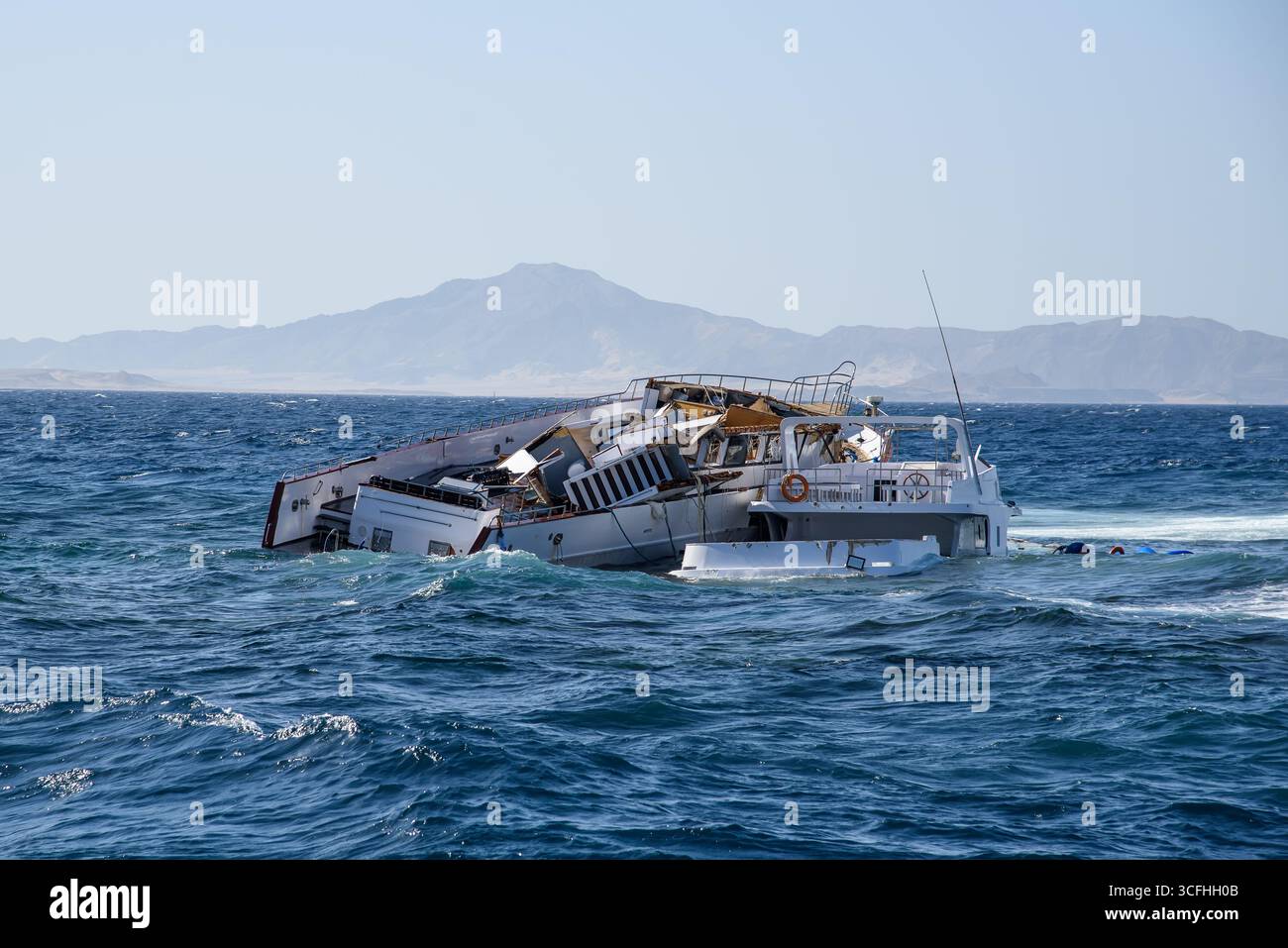 Il relitto di una barca in mare aperto sullo sfondo delle montagne Foto Stock