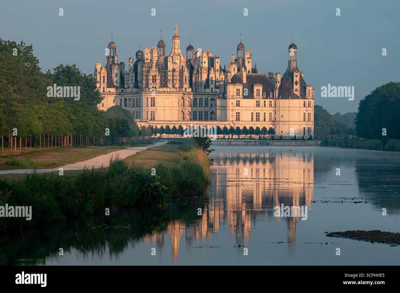Vista a tutto campo del Castello di Chambord e la sua riflessione sull'acqua nella luce mattutina dell'ora d'oro Foto Stock