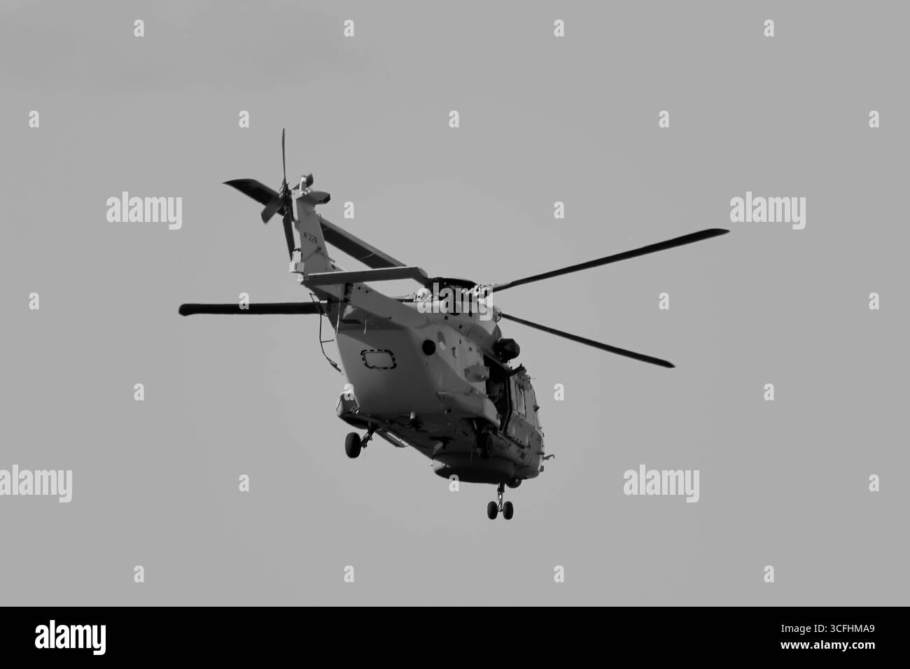 Royal Netherlands Navy NH90 N-326 su Amsterdam, Paesi Bassi, vista posteriore in volo con cambio esteso e sportello laterale aperto, elaborazione in bianco e nero. Foto Stock
