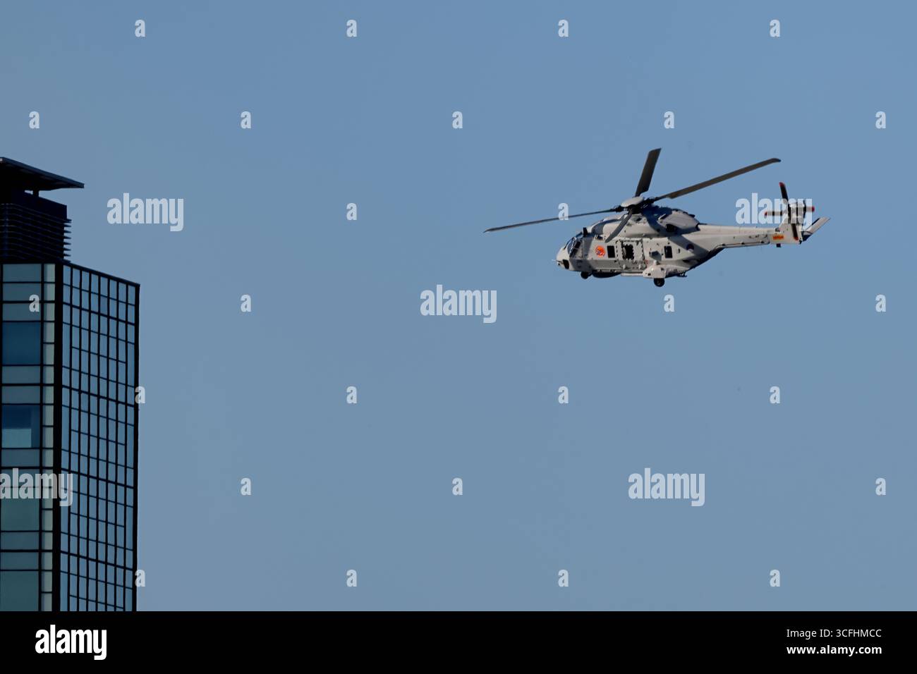 Royal Netherlands Navy NH90 N-326 sorvolando una torre ad Amsterdam, Paesi Bassi, profilo laterale con carrello di atterraggio giù, elicottero marittimo alla luce del giorno. Foto Stock