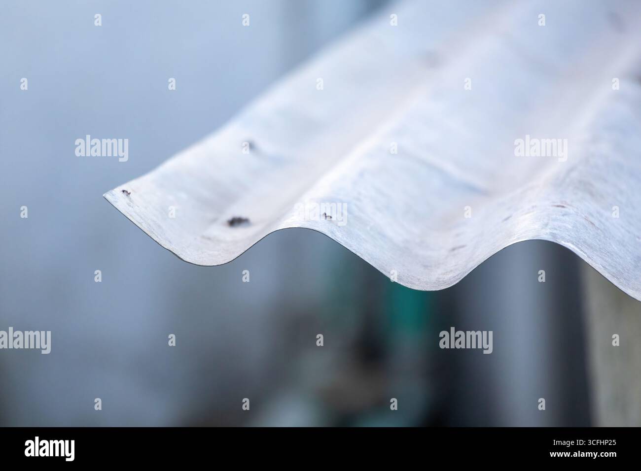 Primo piano di un vecchio foglio di ferro ondulato con sfondo sfocato. Texture ondulate di stagno di Dhew galvanizzato di un tetto di una casa di villaggio in Bangladesh. Foto Stock