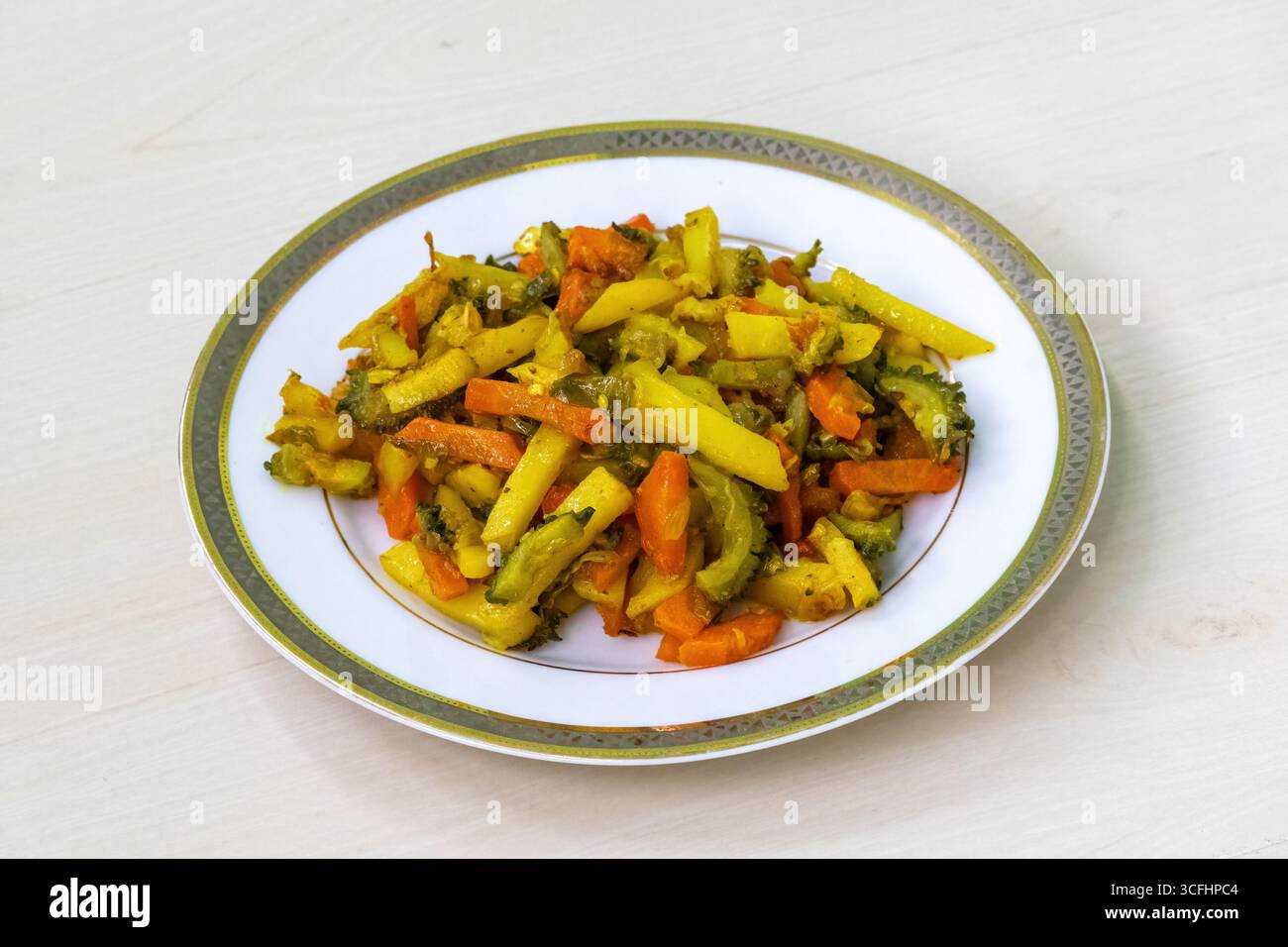 Patate cotte, carote e frittelle dolci su un piatto bianco. Le verdure vengono tritate, mescolate insieme e poi fritte. Questo popolare di bengalese Foto Stock