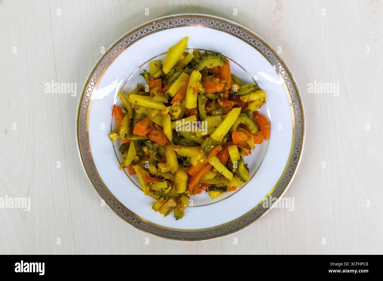 Frittelle di patate, carote e gourd amaro su un piatto bianco. Queste verdure vengono tritate, mescolate insieme e poi fritte. Questo piatto del Bangladesh e' una guarigione Foto Stock