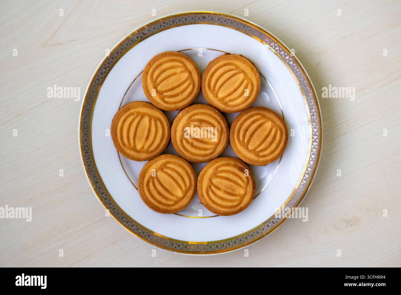 Gustosi biscotti di frumento ripieni di crema di latte serviti su un piatto bianco su sfondo di legno. Vista dall'alto Foto Stock