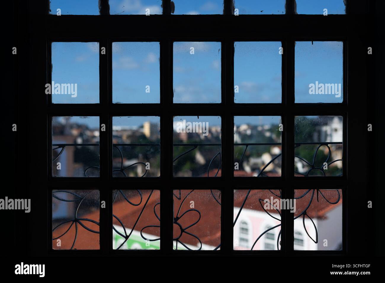 Una vecchia finestra di legno dalle forme quadrate su una città e il cielo sullo sfondo. Sfondo. Brasile. Foto Stock