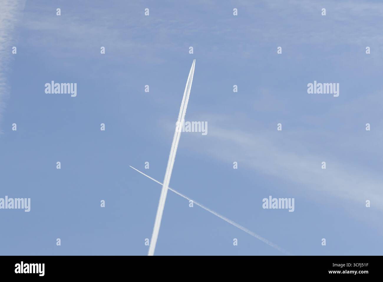 Due aerei passeggeri a reazione con piste di vapore o corrimano che volano in un attraversamento del cielo blu che fa una croce, Inghilterra, Regno Unito Foto Stock