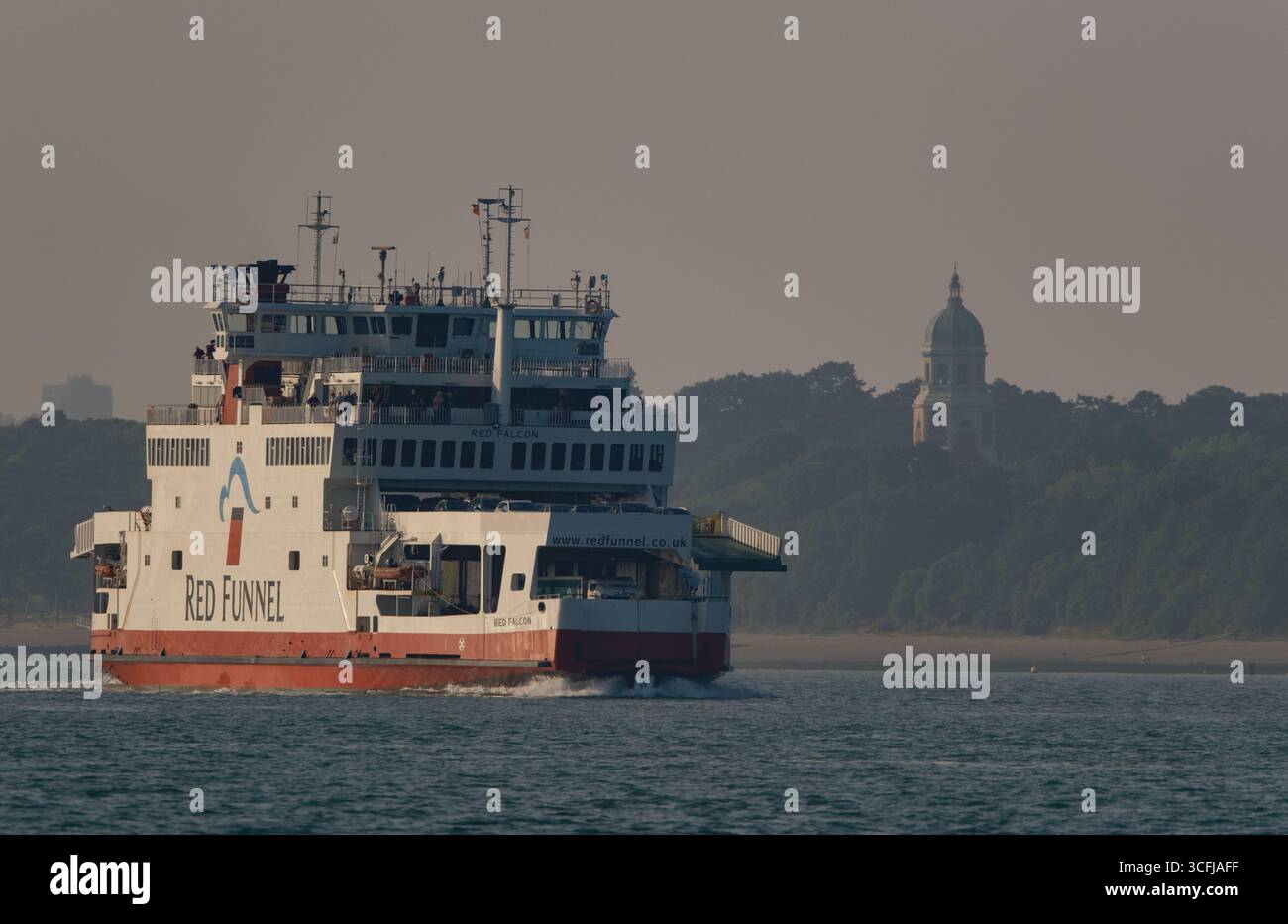 Funivia rossa il traghetto Red Falcon naviga lungo il Solent durante il suo viaggio. L'isola di Wight prende il sole serale con i passeggeri sui ponti. Foto Stock