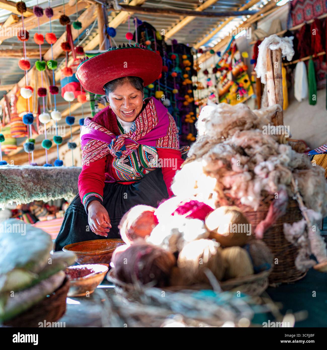 Donna andina che prepara lana e filati a Cusco, Perù. Artigianato tessile tradizionale con fibre naturali, colori vivaci e patrimonio culturale. Foto Stock