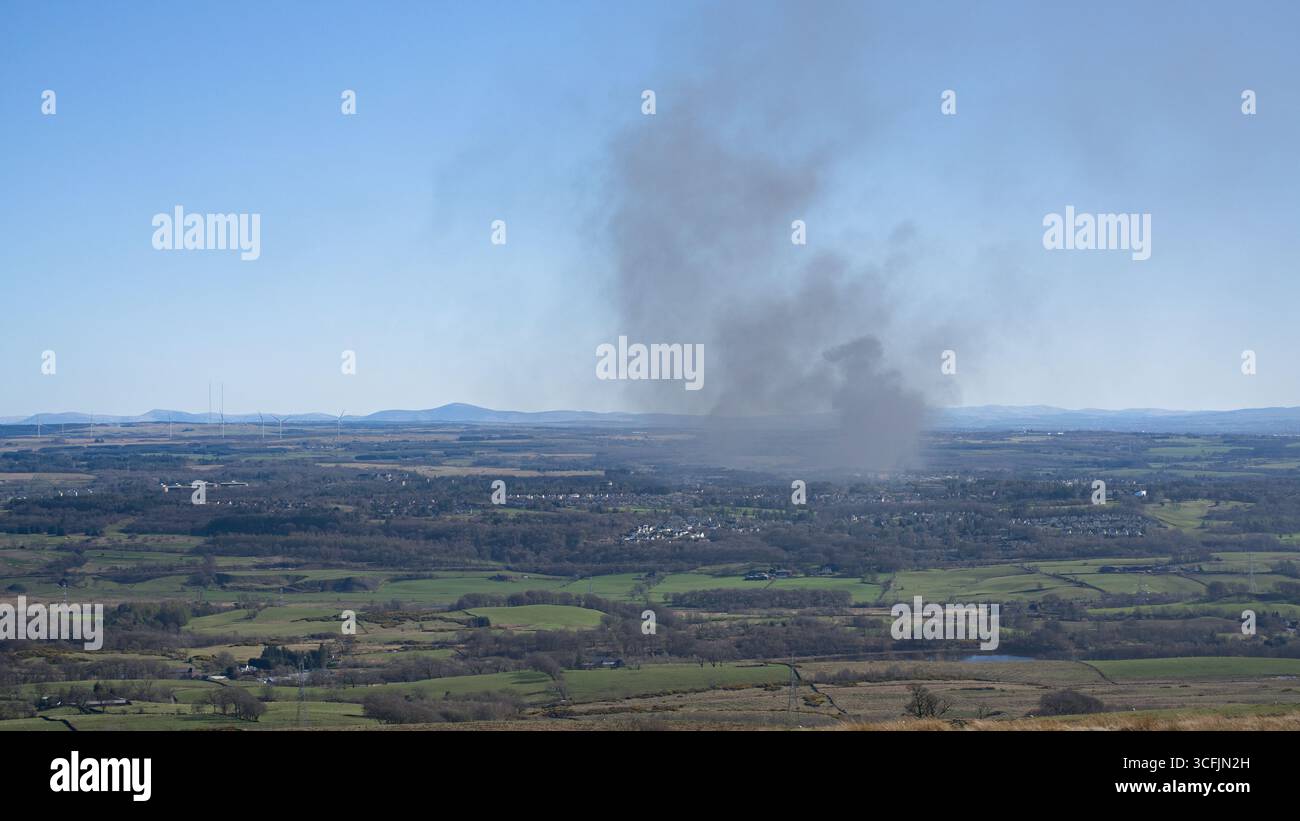 Punto panoramico sulla strada "Tak-ma-Doon" sopra Kilsyth, Scozia. Rif. Mappa sistema operativo NS 734 811. 1° aprile 2025. Un pennacchio di fumo da un incendio in una zona industriale. Foto Stock