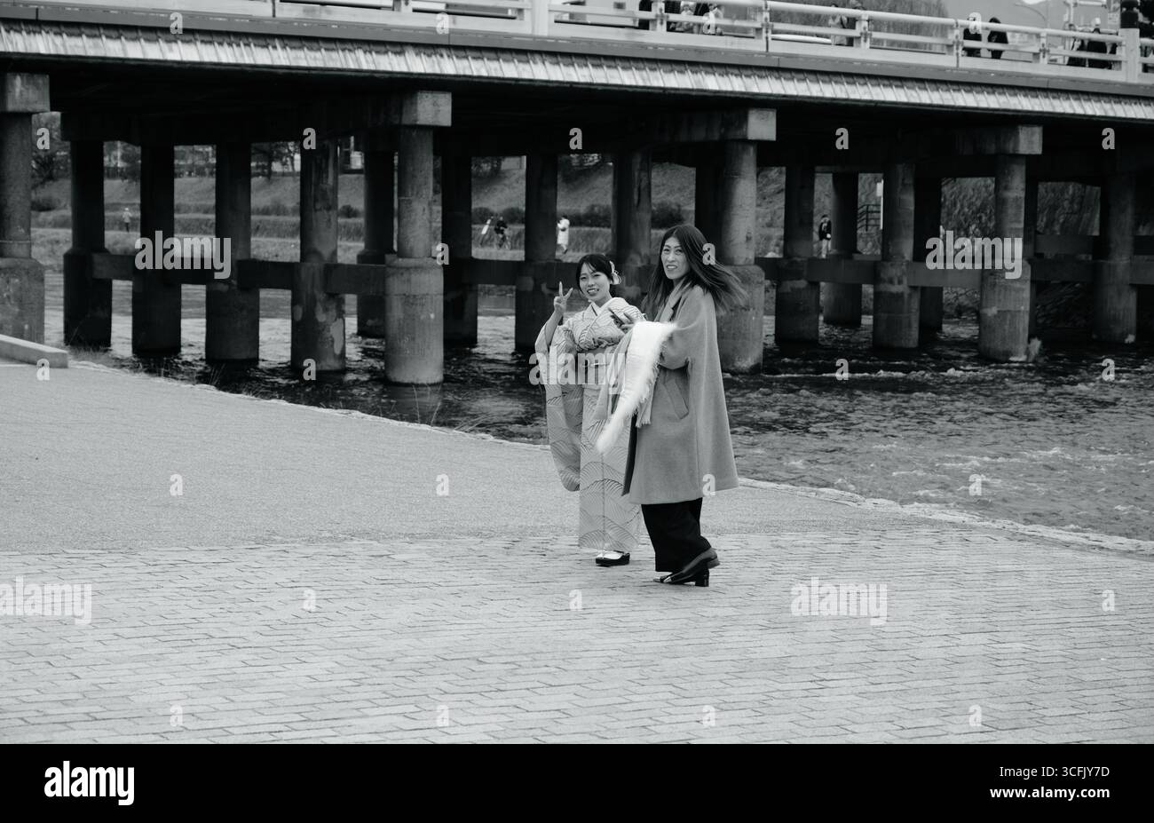 Due donne, una in kimono, condividono un momento di gioia lungo il fiume Kamo Foto Stock
