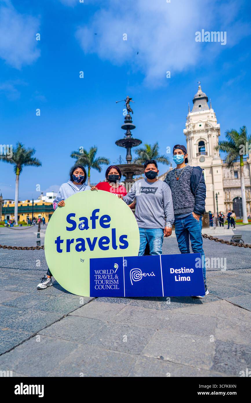 Gruppo di persone con cartello Safe Travels in Plaza Mayor Lima Perù, che promuove la sicurezza del turismo e la fiducia dei viaggiatori nel centro della città. Foto Stock