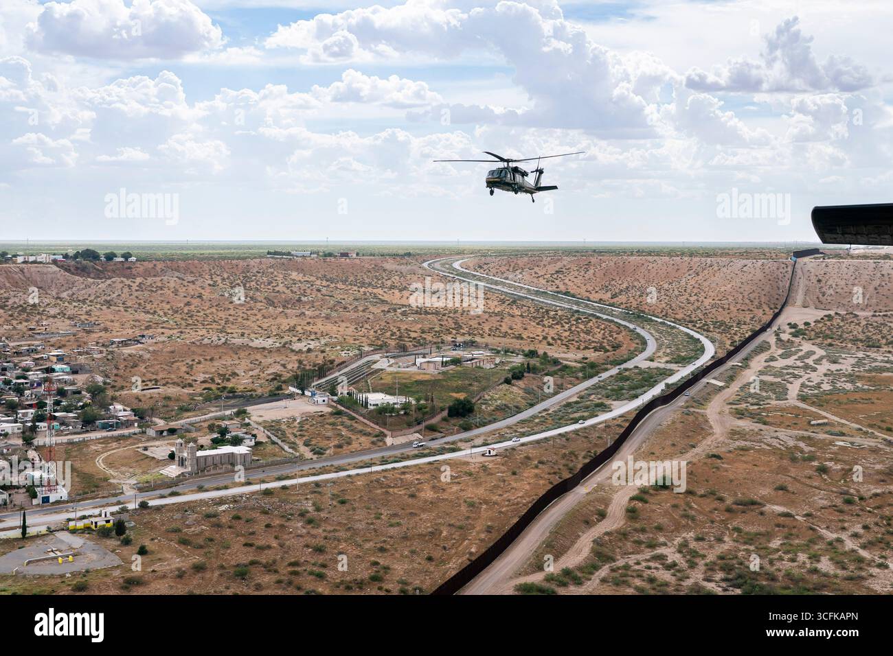 Il segretario del Dipartimento per la sicurezza interna (DHS) Kristi Noem ha viaggiato su un jet militare e poi su un elicottero fino al muro del confine meridionale degli Stati Uniti, dove ha in mano una foto - sotto la direzione del presidente Donald Trump - per dipingere il muro d'acciaio del confine nero a Santa Teresa, New Mexico. Noem è stato assistito da membri in uniforme degli agenti della dogana e della protezione delle frontiere degli Stati Uniti. La vernice nera doveva raccogliere l’energia del sole per rendere l’acciaio del muro più caldo al tatto – quindi più difficile per i clandestini scalare. La vernice, tuttavia, veniva applicata solo sul lato statunitense del muro di confine. Foto Stock