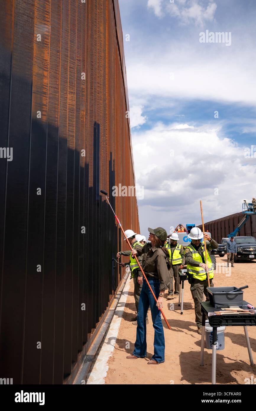 Il segretario del Dipartimento per la sicurezza interna (DHS) Kristi Noem ha viaggiato su un jet militare e poi su un elicottero fino al muro del confine meridionale degli Stati Uniti, dove ha in mano una foto - sotto la direzione del presidente Donald Trump - per dipingere il muro d'acciaio del confine nero a Santa Teresa, New Mexico. Noem è stato assistito da membri in uniforme degli agenti della dogana e della protezione delle frontiere degli Stati Uniti. La vernice nera doveva raccogliere l’energia del sole per rendere l’acciaio del muro più caldo al tatto – quindi più difficile per i clandestini scalare. La vernice, tuttavia, veniva applicata solo sul lato statunitense del muro di confine. Foto Stock