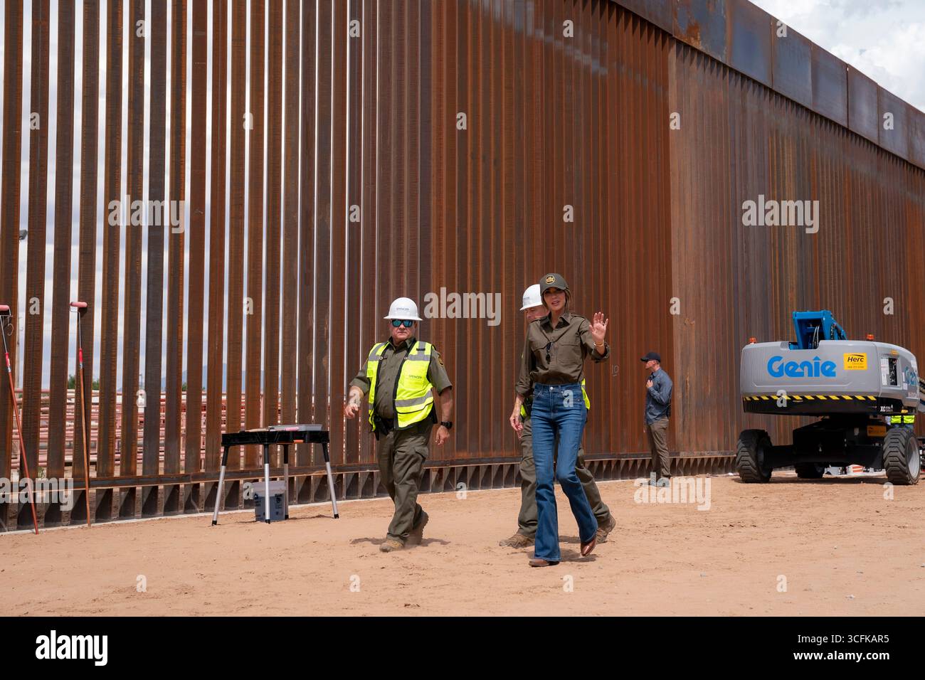 Il segretario del Dipartimento per la sicurezza interna (DHS) Kristi Noem ha viaggiato su un jet militare e poi su un elicottero fino al muro del confine meridionale degli Stati Uniti, dove ha in mano una foto - sotto la direzione del presidente Donald Trump - per dipingere il muro d'acciaio del confine nero a Santa Teresa, New Mexico. Noem è stato assistito da membri in uniforme degli agenti della dogana e della protezione delle frontiere degli Stati Uniti. La vernice nera doveva raccogliere l’energia del sole per rendere l’acciaio del muro più caldo al tatto – quindi più difficile per i clandestini scalare. La vernice, tuttavia, veniva applicata solo sul lato statunitense del muro di confine. Foto Stock