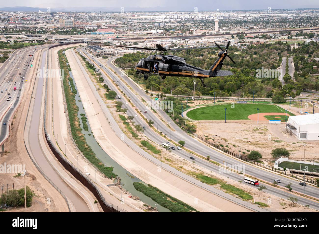 Il segretario del Dipartimento per la sicurezza interna (DHS) Kristi Noem ha viaggiato su un jet militare e poi su un elicottero fino al muro del confine meridionale degli Stati Uniti, dove ha in mano una foto - sotto la direzione del presidente Donald Trump - per dipingere il muro d'acciaio del confine nero a Santa Teresa, New Mexico. Noem è stato assistito da membri in uniforme degli agenti della dogana e della protezione delle frontiere degli Stati Uniti. La vernice nera doveva raccogliere l’energia del sole per rendere l’acciaio del muro più caldo al tatto – quindi più difficile per i clandestini scalare. La vernice, tuttavia, veniva applicata solo sul lato statunitense del muro di confine. Foto Stock